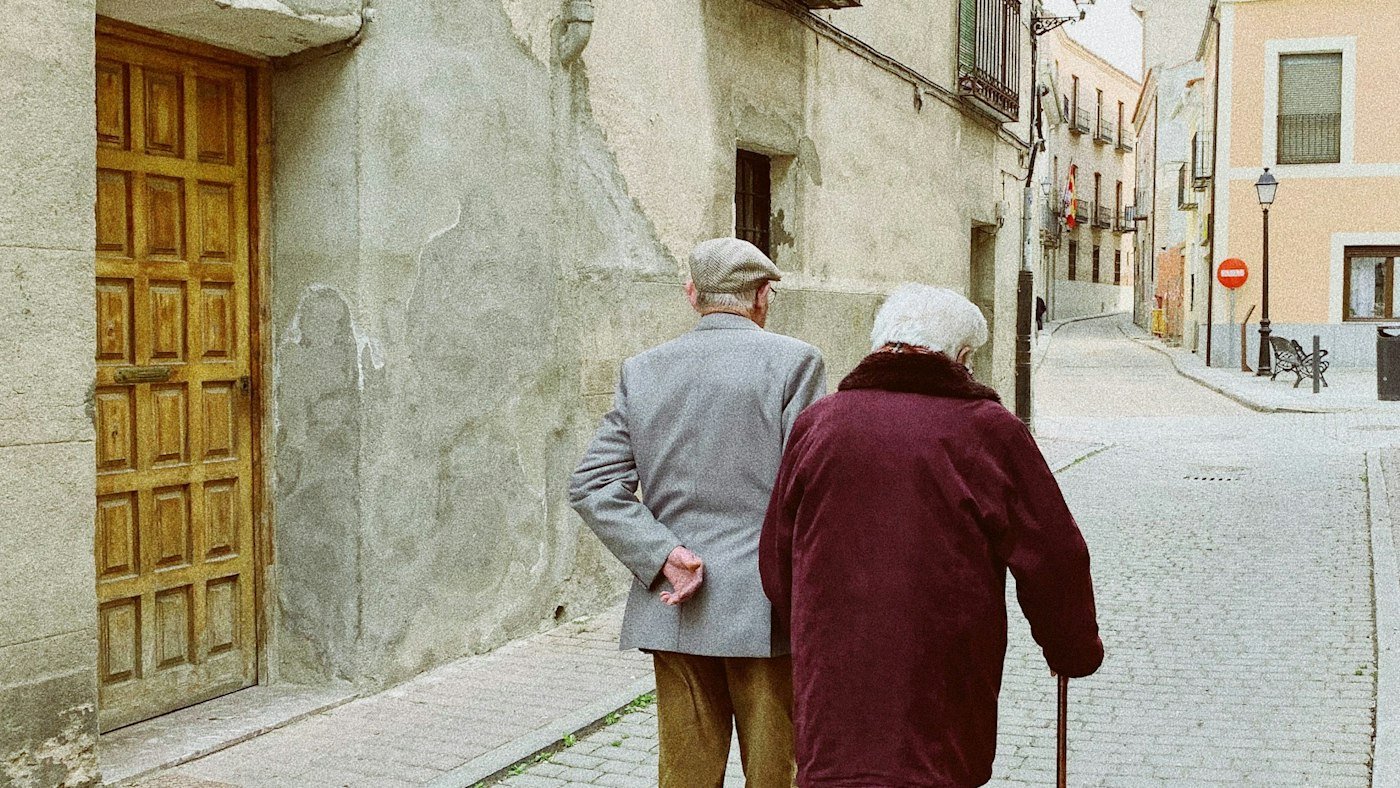 Pareja de adultos mayores caminando con bastón