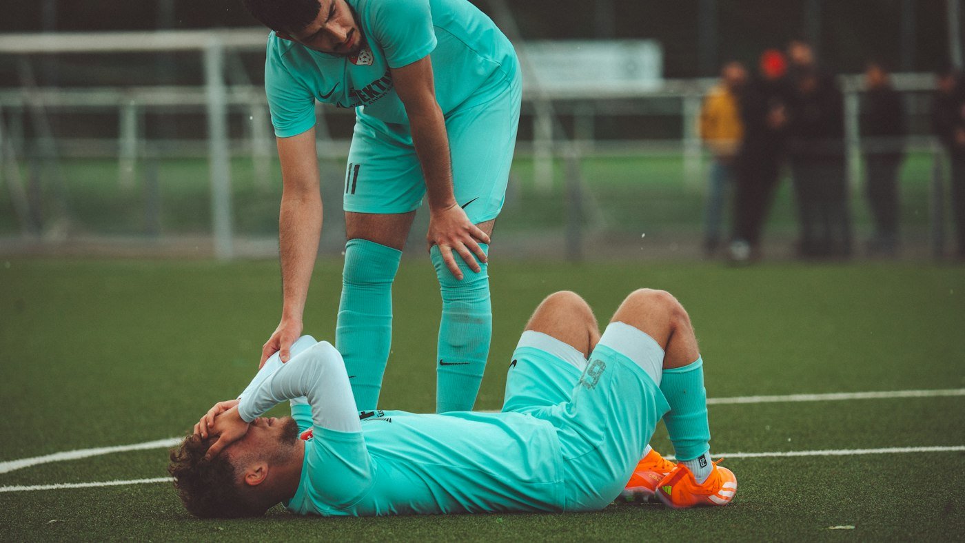 Jugadora de fútbol en el suelo tras una lesión de rodilla